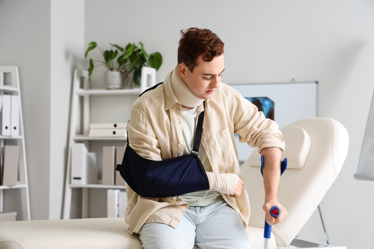 Young man with arm sling and crutch after filing a premises liability claim in Brooklyn NY