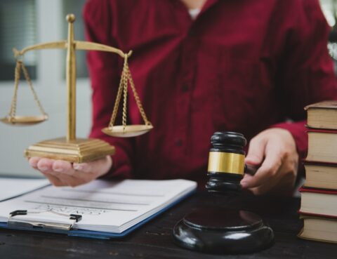 Attorney holding scales of justice next to a gavel representing the personal injury settlement vs trial decision