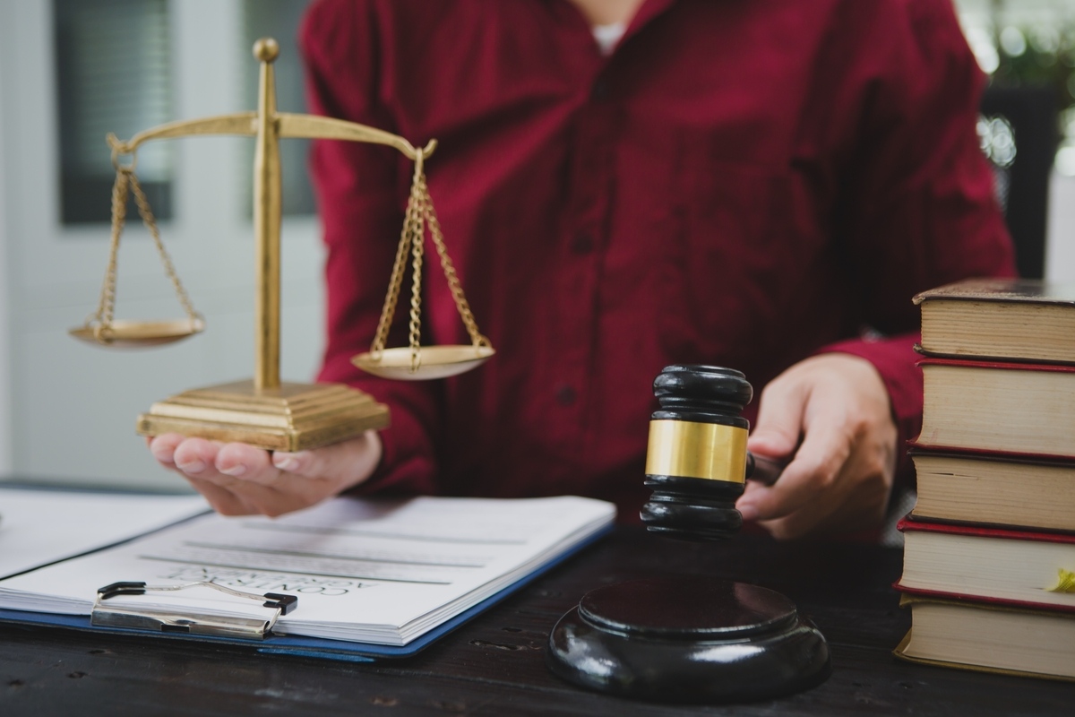 Attorney holding scales of justice next to a gavel representing the personal injury settlement vs trial decision
