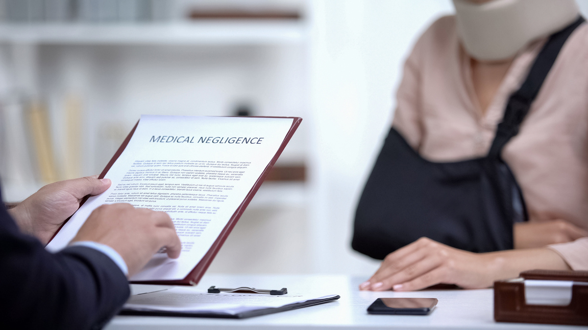 Medical malpractice lawyer in Brooklyn NY reviewing a medical negligence document with an injured patient in a sling