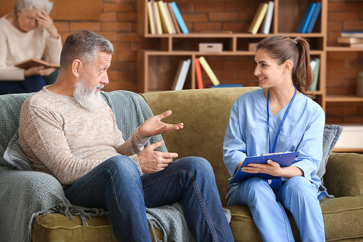Nursing home abuse lawyer in Brooklyn NY representing an elderly resident discussing concerns with a caregiver in a nursing facility