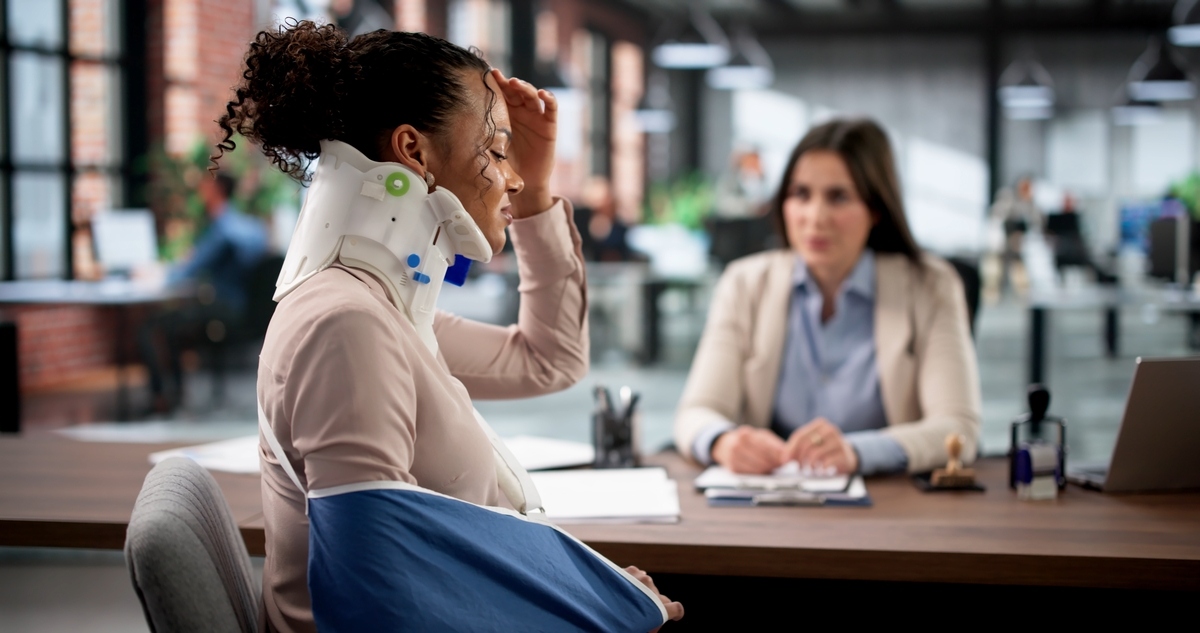 Personal injury lawyer in Manhattan NY consulting with an injured client wearing a neck brace and arm sling
