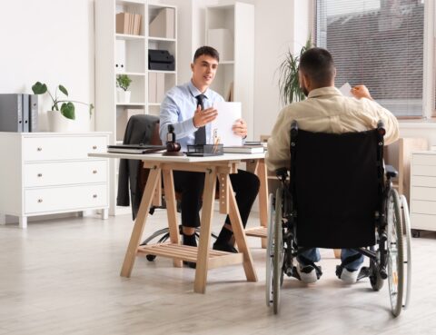 Attorney discussing a personal injury letter of protection with a wheelchair-bound client in a law office