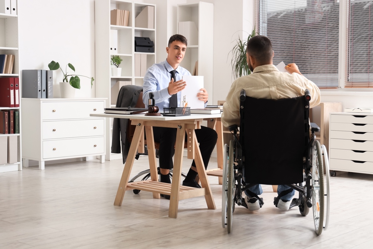 Attorney discussing a personal injury letter of protection with a wheelchair-bound client in a law office