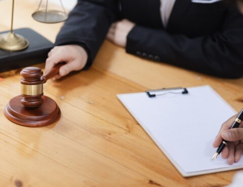 Personal injury settlement vs trial consultation with an attorney holding a gavel and reviewing legal documents