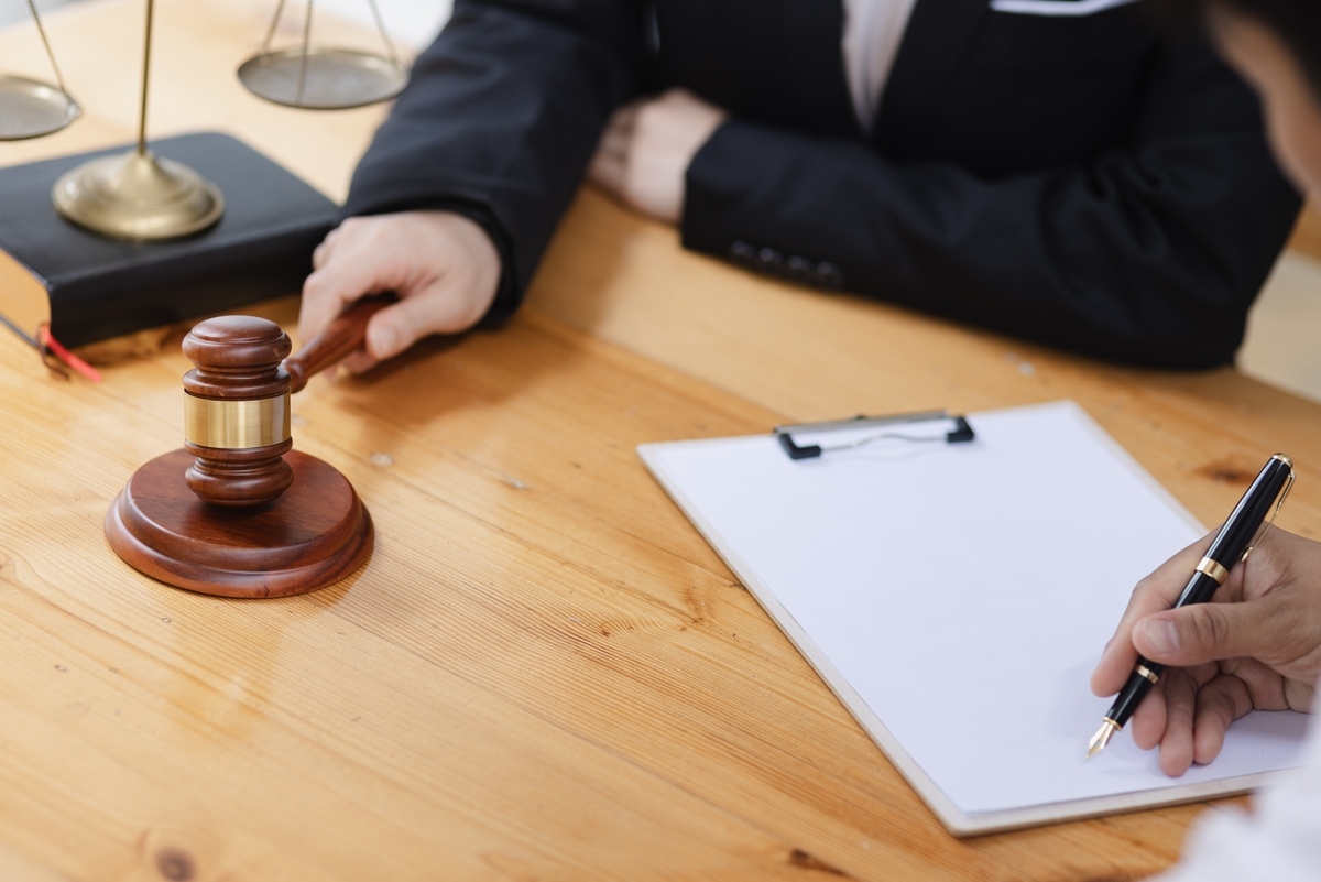 Personal injury settlement vs trial consultation with an attorney holding a gavel and reviewing legal documents