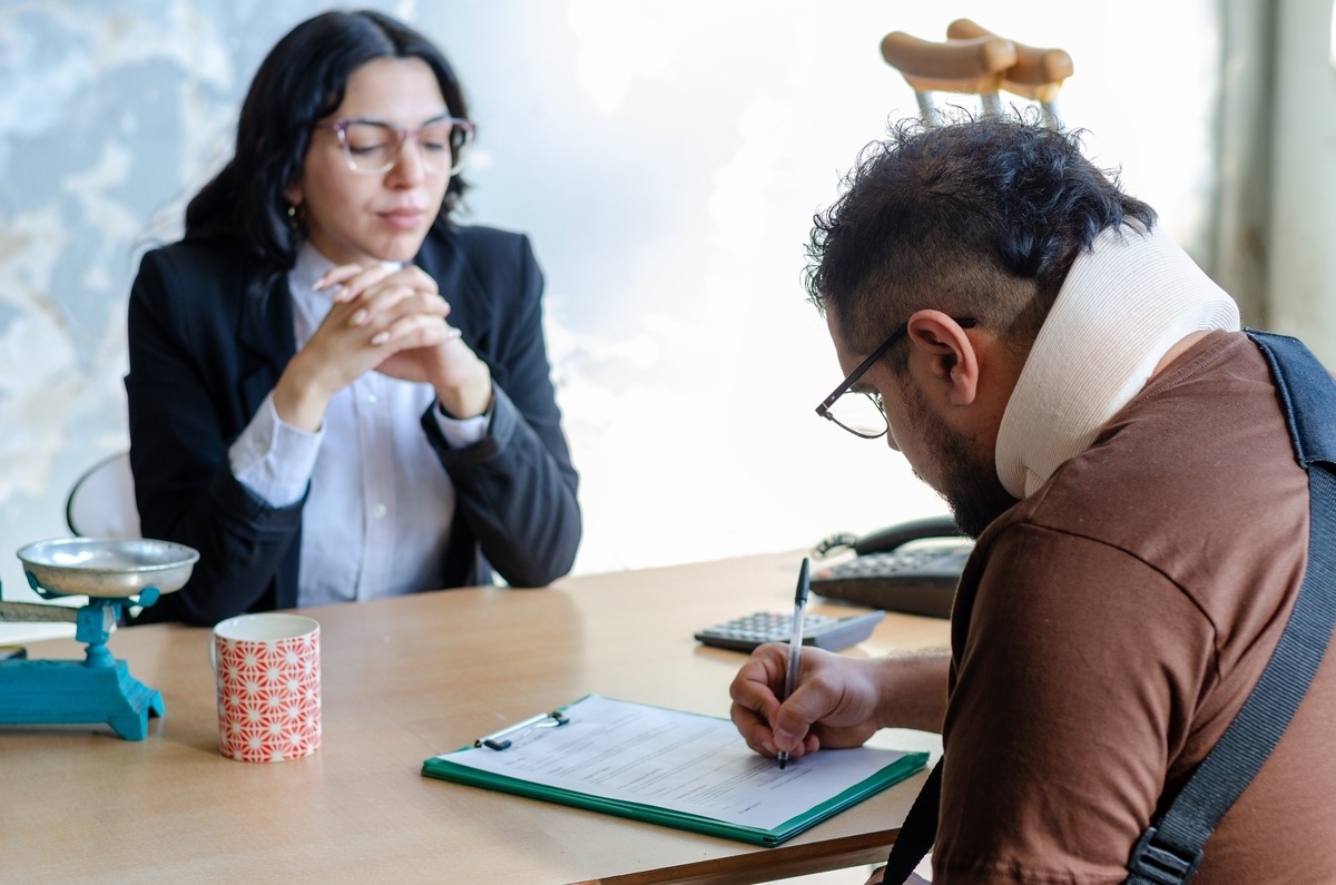 Personal injury lawyer in Jersey City NJ consulting with an injured client wearing a neck brace signing legal documents