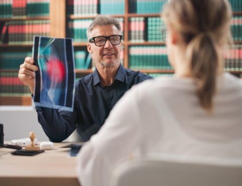 Attorney reviewing X-ray imaging with a client during a pre-existing condition injury claim consultation
