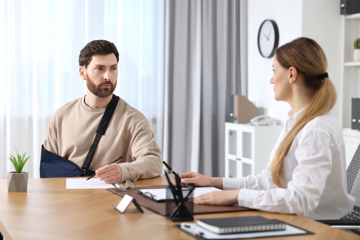 Injured client with arm in a sling discussing a bicycle accident claim in NY with an attorney