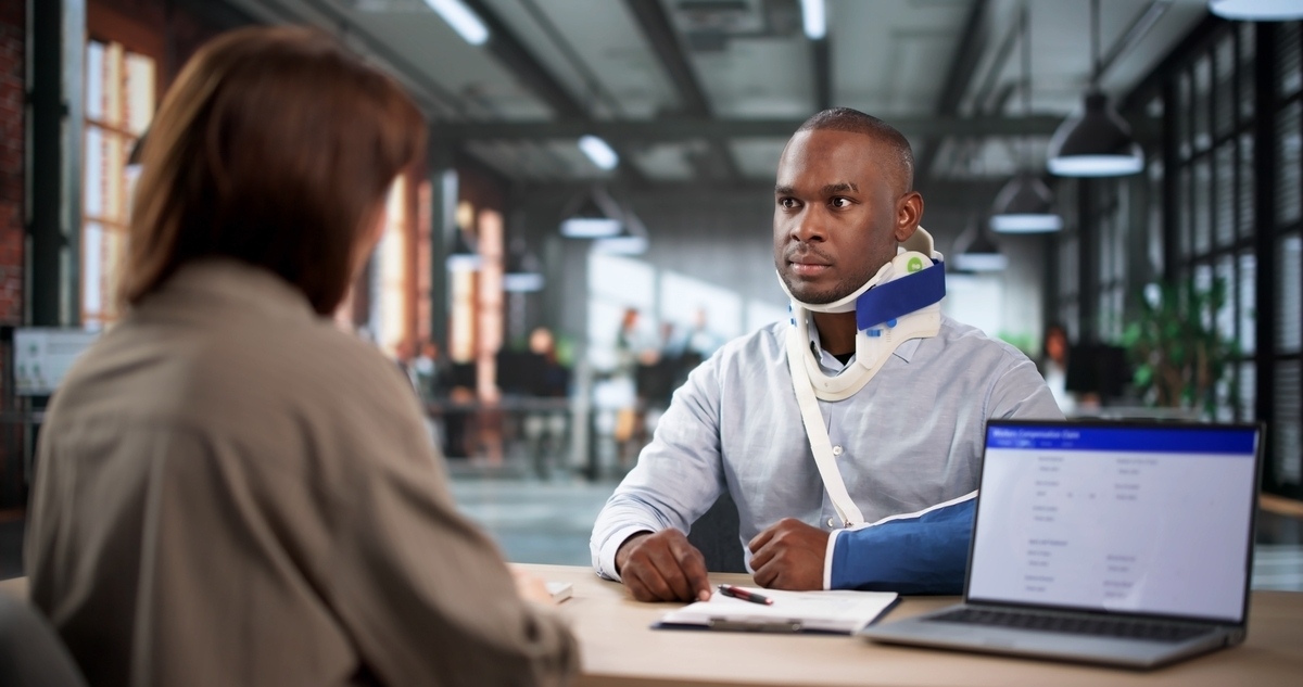 Motorcycle accident lawyer in Elizabeth NJ consulting with an injured client wearing a neck brace and arm sling in a legal office