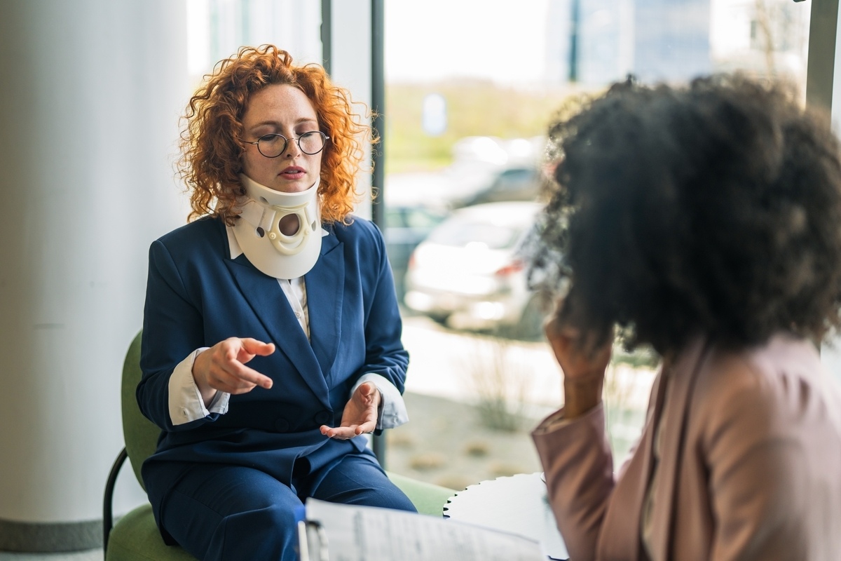 Passenger injury claim consultation with an injured woman wearing a neck brace meeting with a legal professional