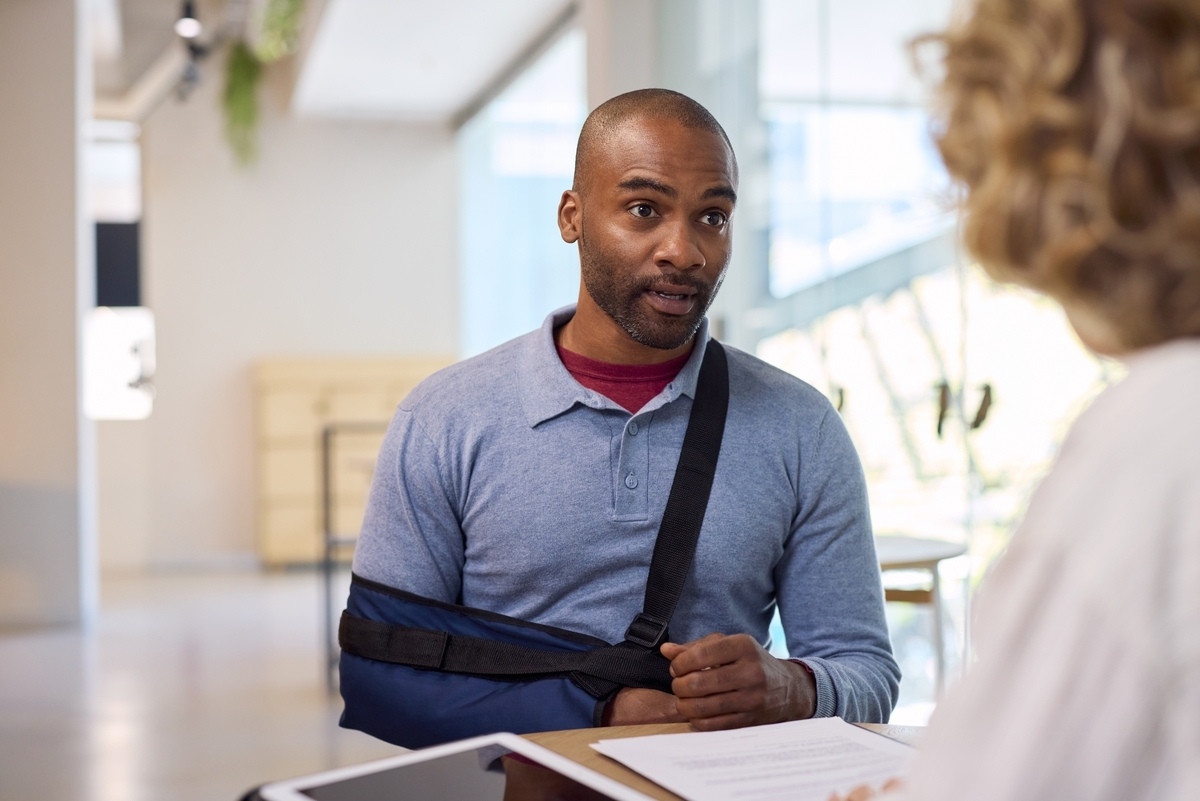 Pedestrian accident lawyer in Flushing NY consulting with an injured client wearing an arm sling