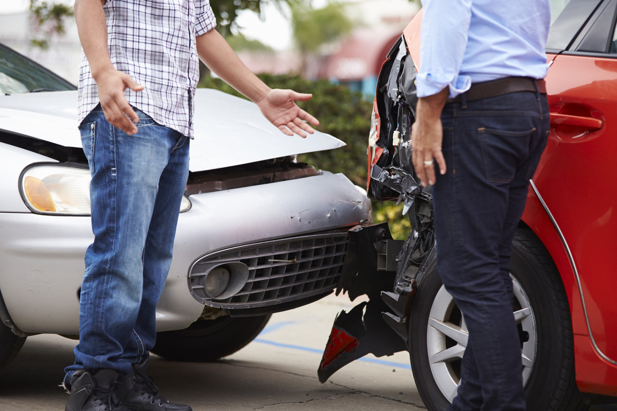 Two drivers discussing car accident fault in NY next to their damaged vehicles